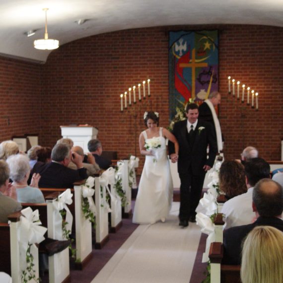 Couple walking down wedding aisle after just getting married at altar