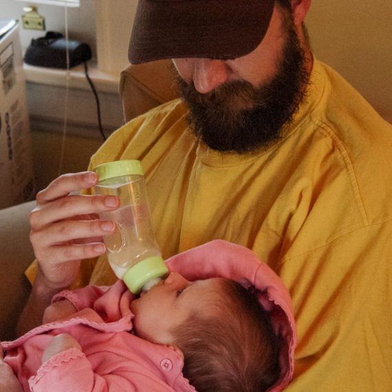 Man feeds bottle to infant