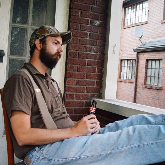 A man holds a beer and poses for a shot to look pensive