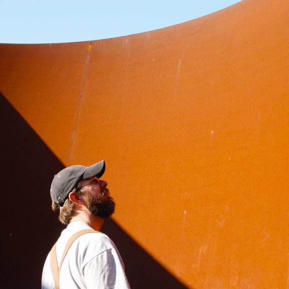 Bearded man in front of Serra sculpture