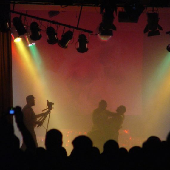 Silhouettes of gay bears performing on stage for a contest