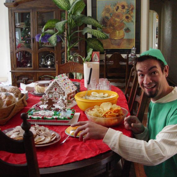 Man dressed as elf stealing food from the Christmas table