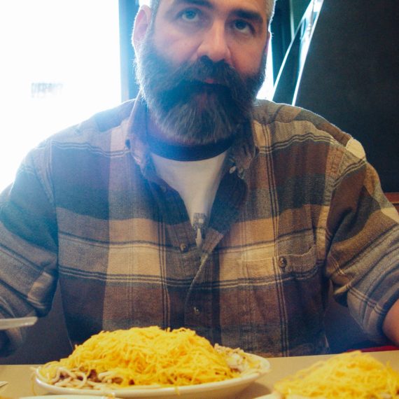 Bearded man at table with a pile of shredded cheese