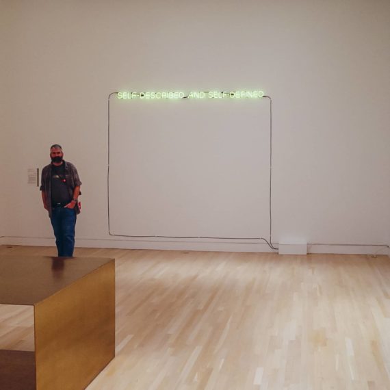 Joseph Kosuth neon art that reads "Self-Defined and Self-Described"