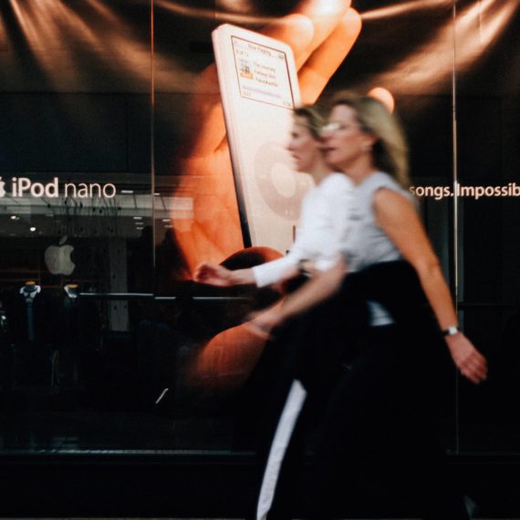 Two mall walkers in front of Apple Store in 2005 with a large iPod nano display