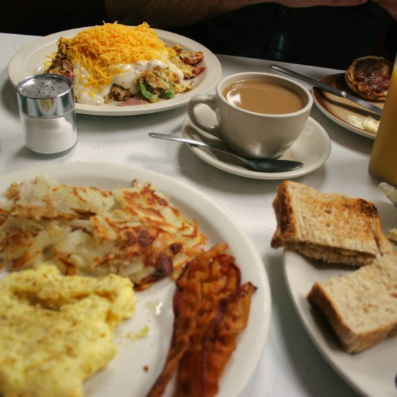 Breakfast plates and coffee fill up a diner table