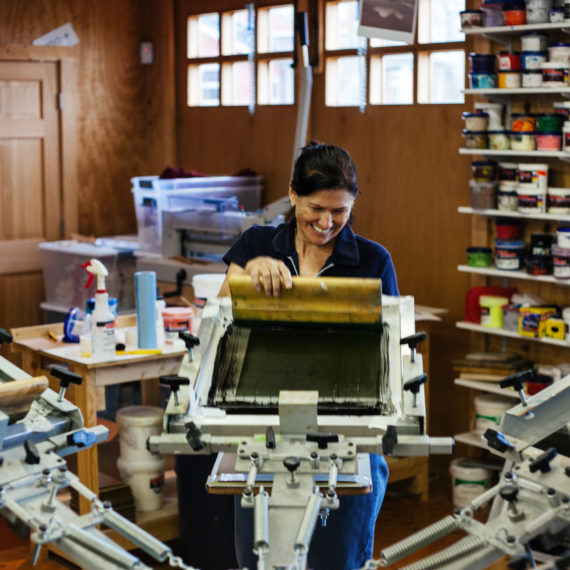 A woman on a screen printing press