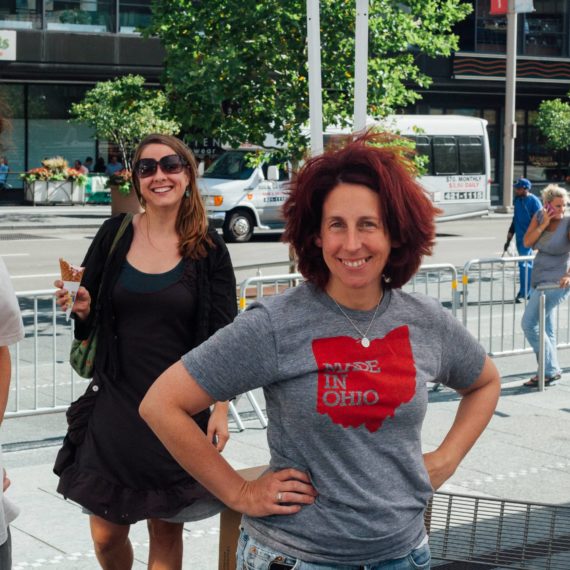 A woman stands akimbo wearing a shirt that says MADE IN OHIO. The wind rustles her hair