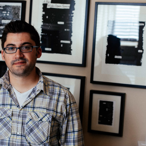 A man in front of framed artwork