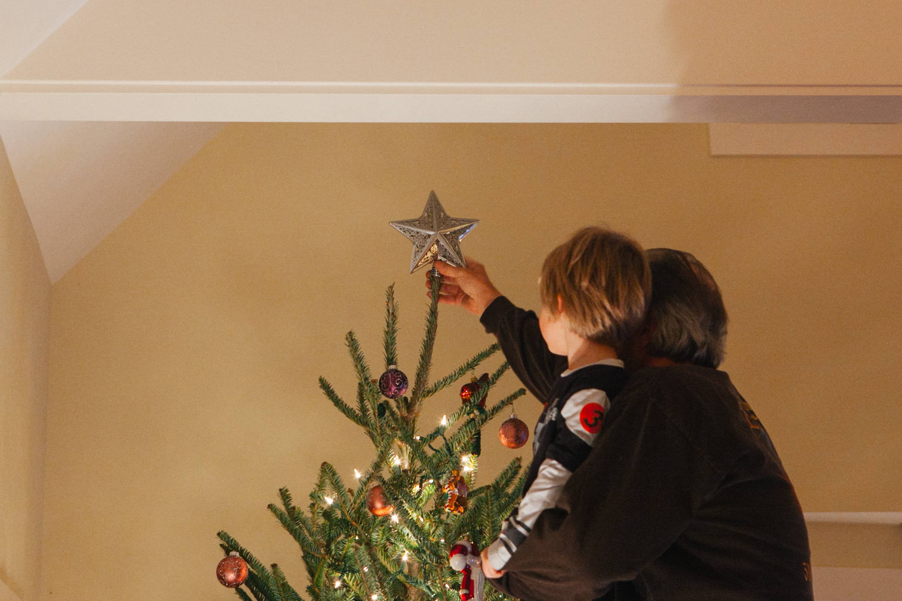 Father and son put star on tree