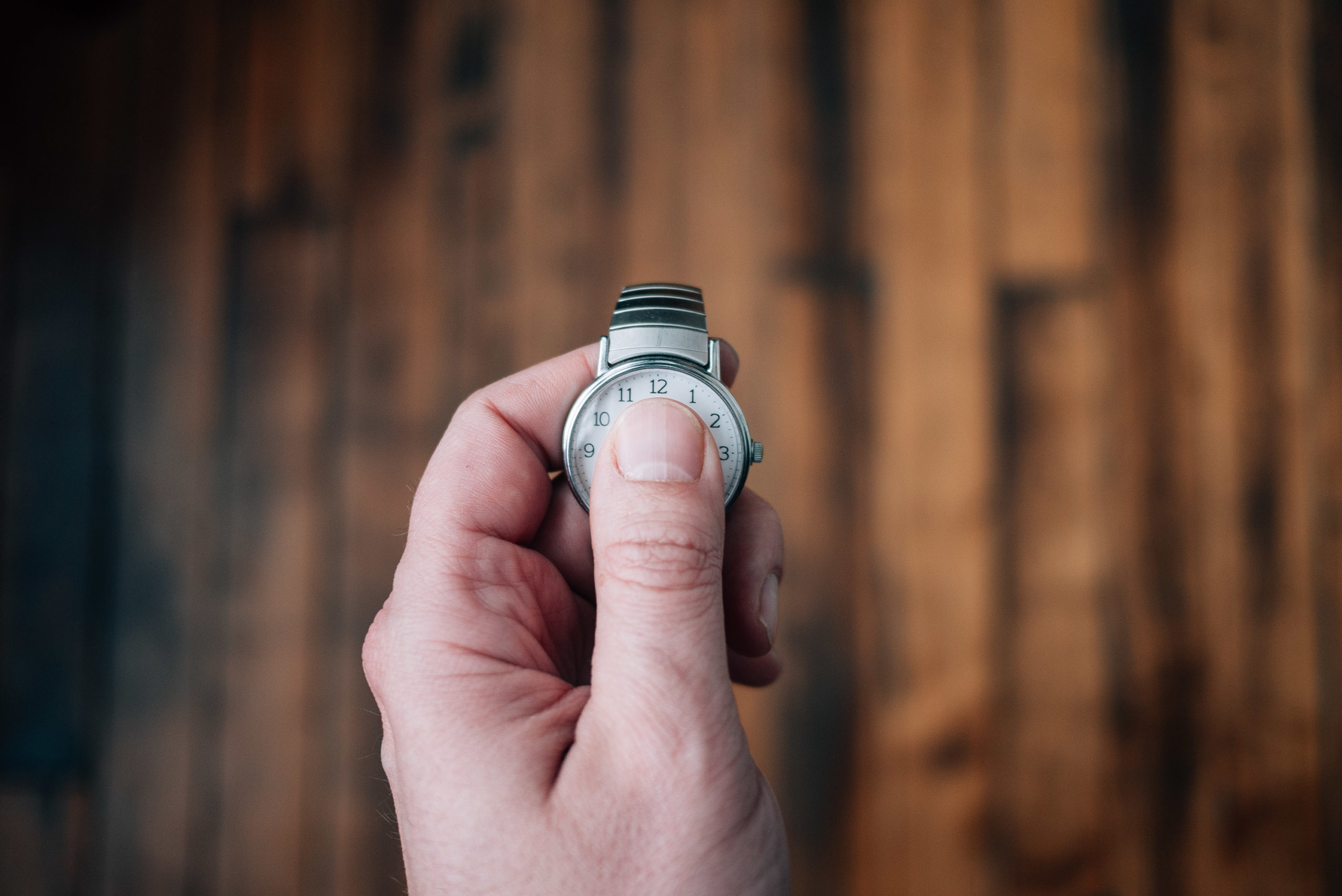 A thumb partially covering the face of a watch