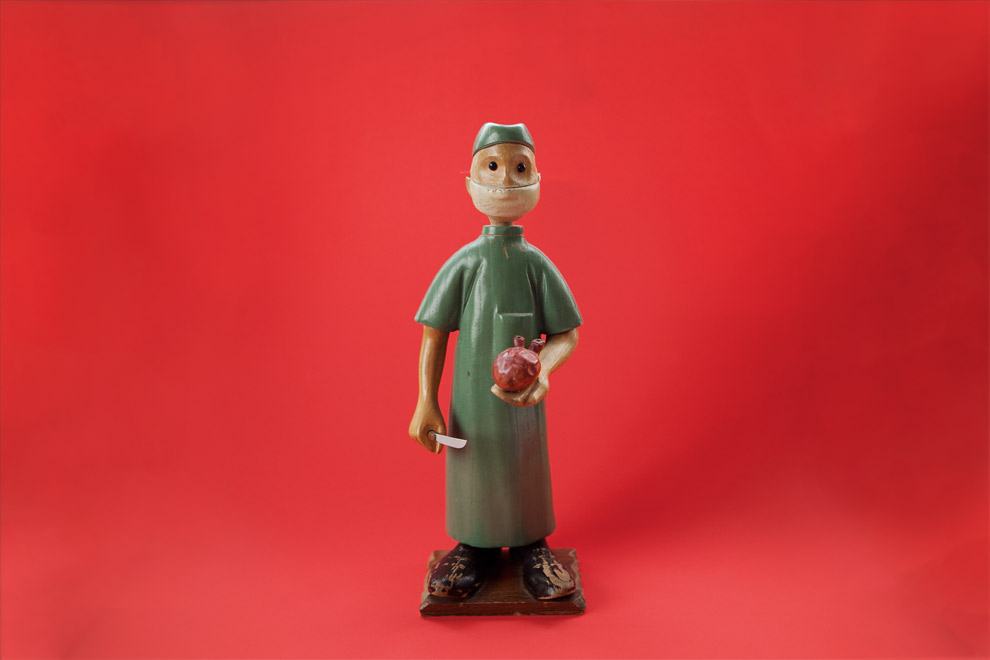 A wooden figure of a doctor on a red background