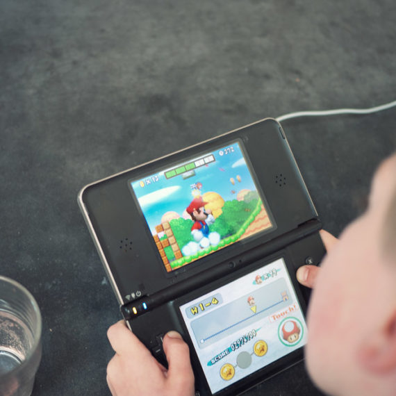 A young man plays Mario on a Nintendo DS