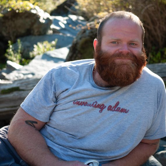 Man with red beard smiles creekside in Northern California