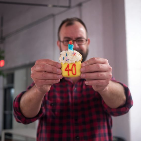 Man holds up cookie with 40 written in icing