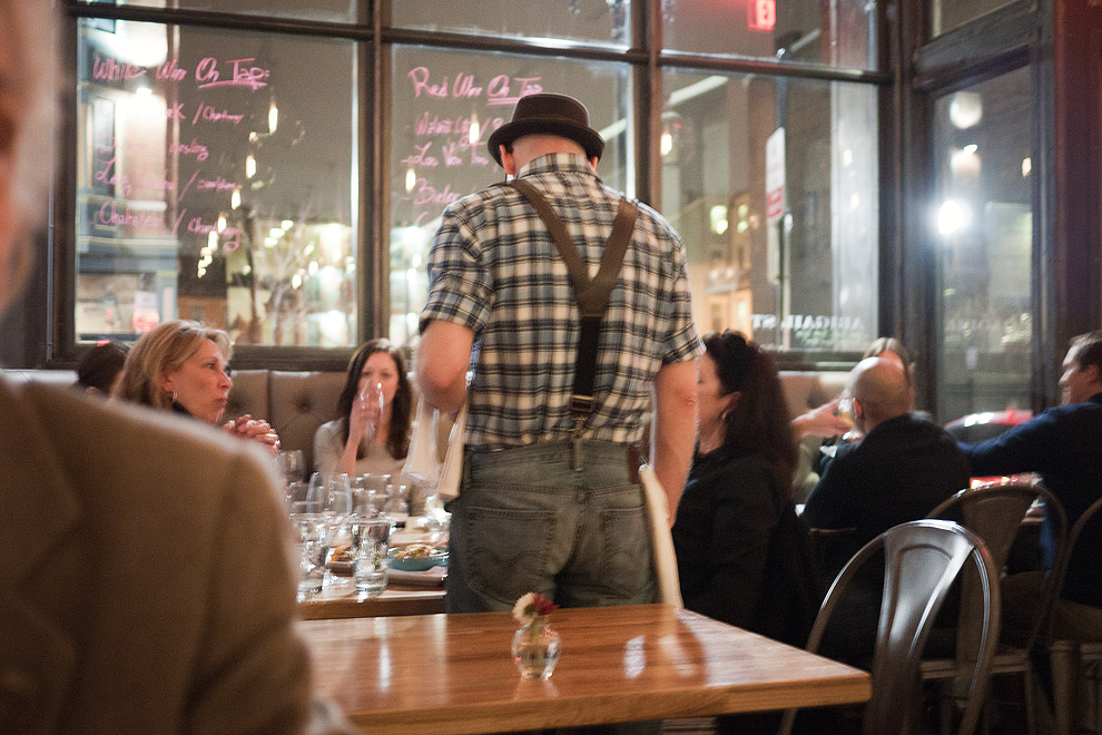 A server in suspenders waits on a table