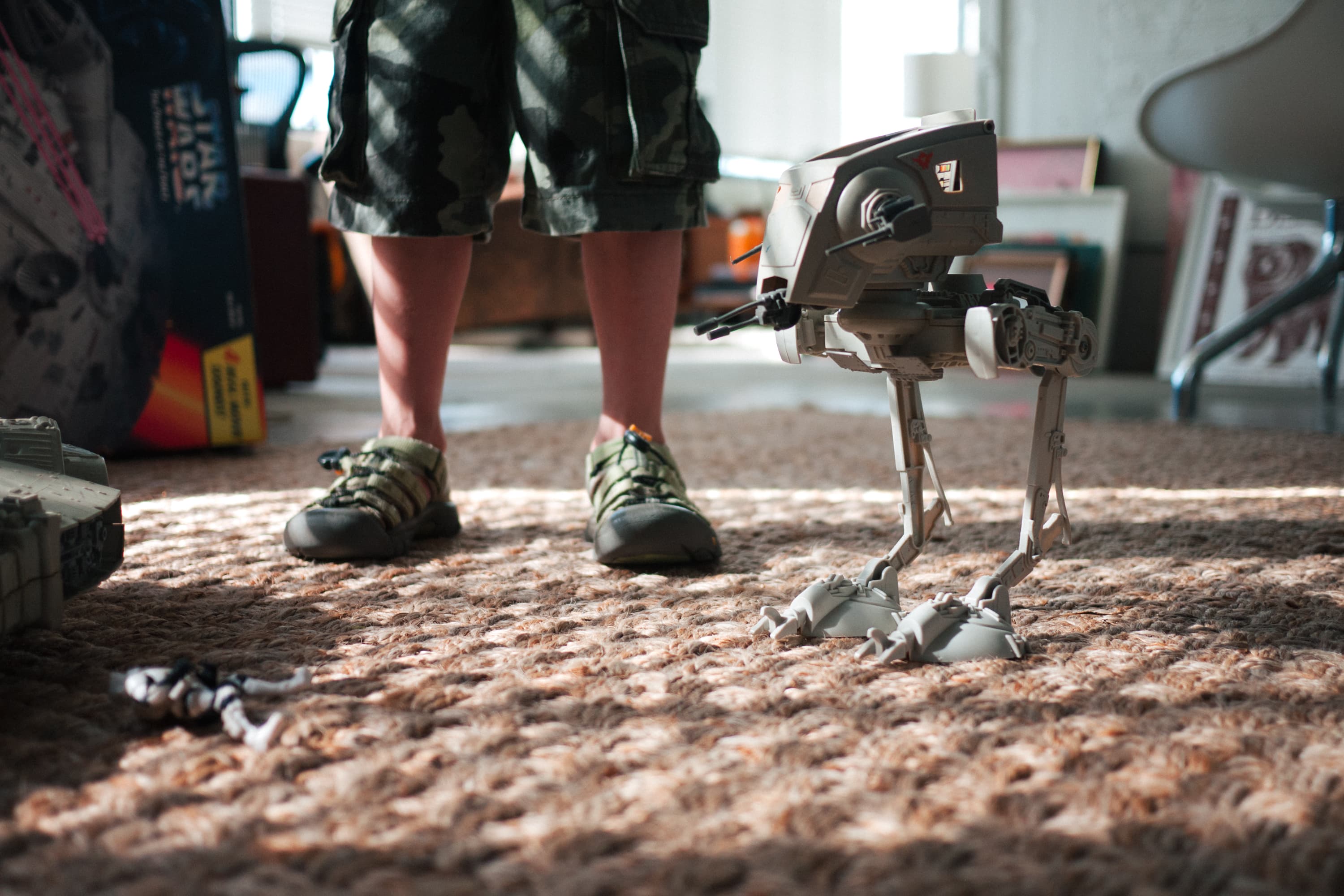 Young person stands next to a toy Star Wars AT-ST