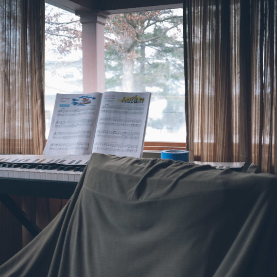 music stand by a keyboard and curtains and a window