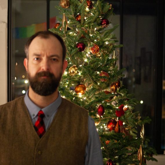 Man with beard takes blurry selfie in front of Christmas tree