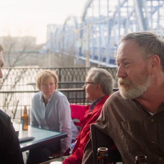 Men regarding each other with the Ohio River as a backdrop