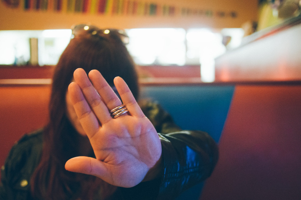 A woman holds upper hand to avoid getting a photo taken