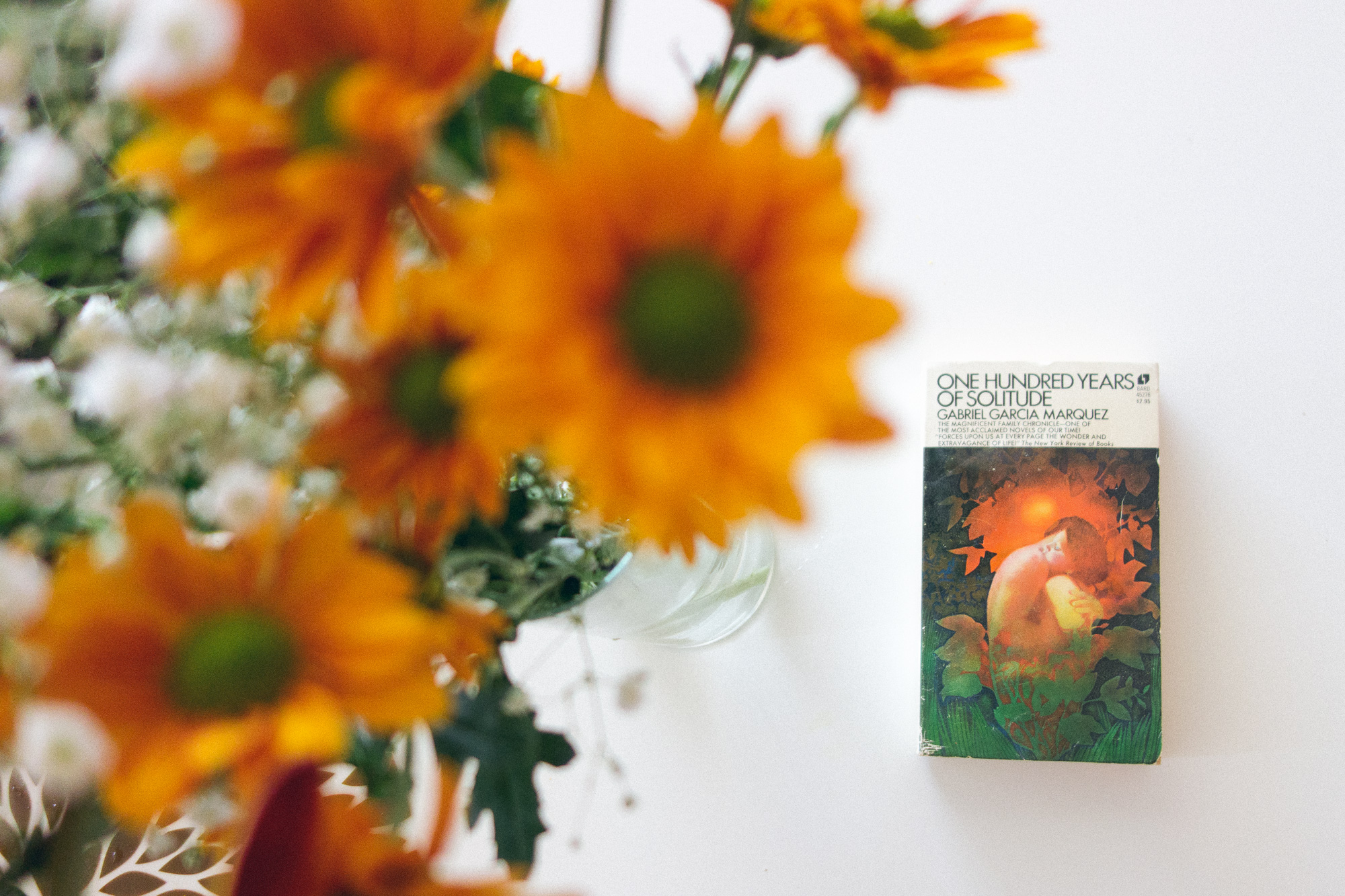 100 Years of Solitude book and some orange flowers