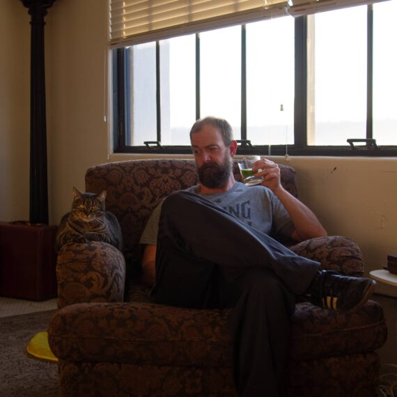 Man in chair with cocktail and cat