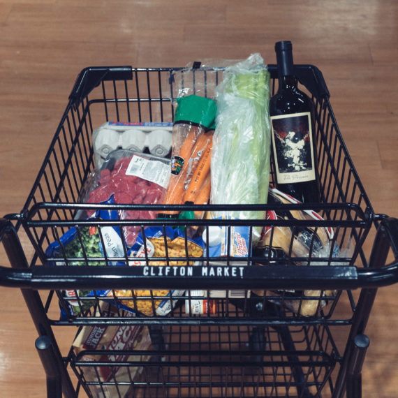 Grocery cart filled with eggs, vegetables and a bottle of wine