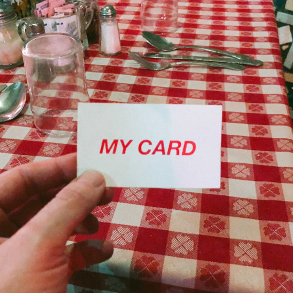 A man’s hand holding the card that reads my card