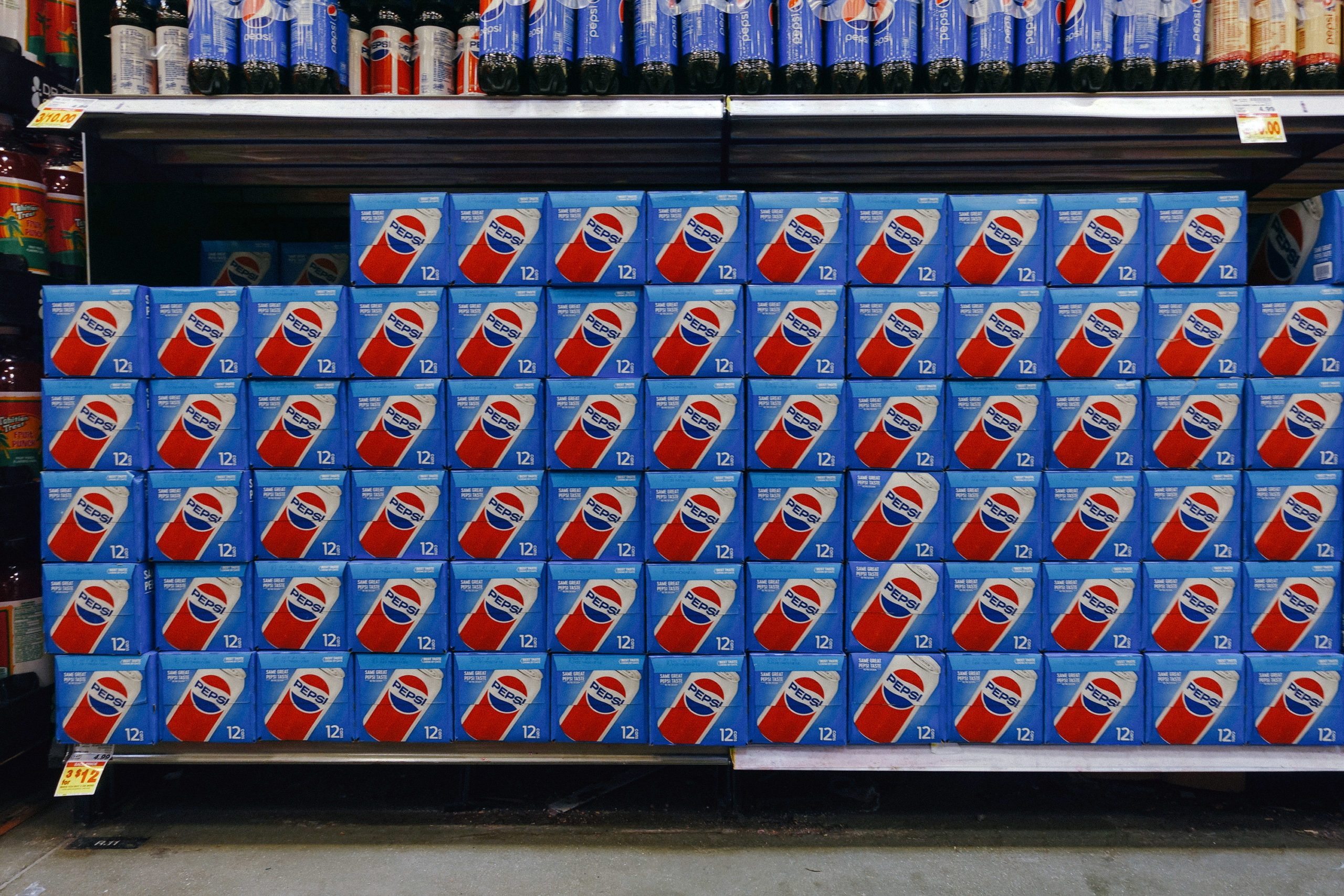 A shelf filled with 12 packs of Pepsi