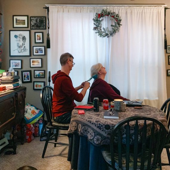 A brother puts his sister’s hair in a braid