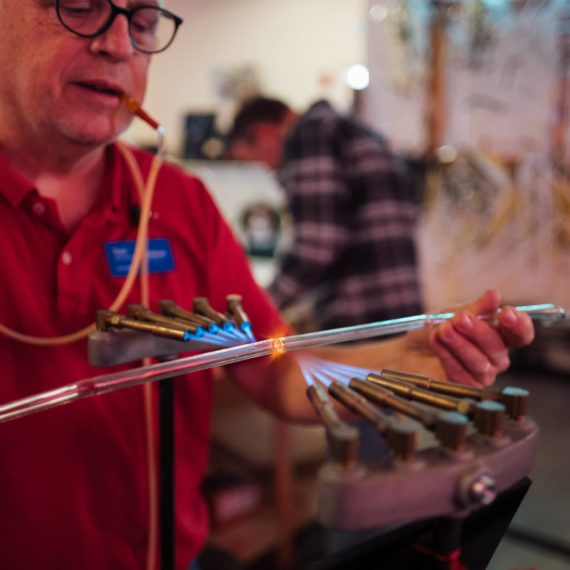 Man expertly bends neon tube of glass