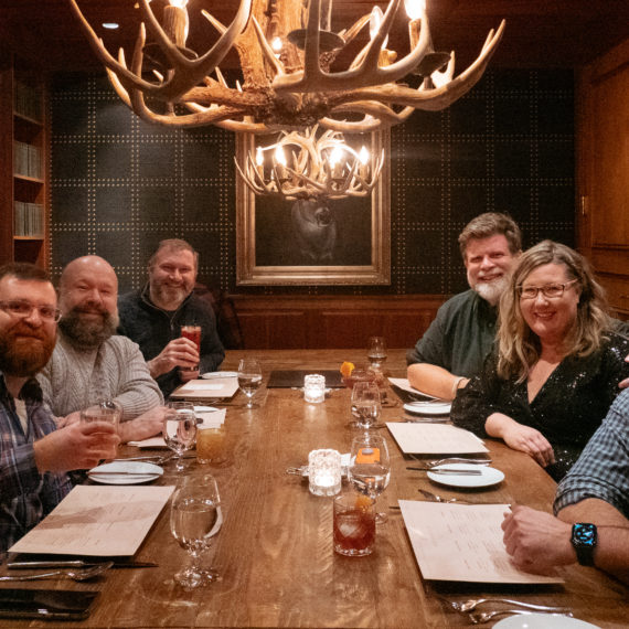 A group of bearded men and a woman at a restaurant table