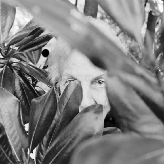 Woman hiding behind leaves of a magnolia tree