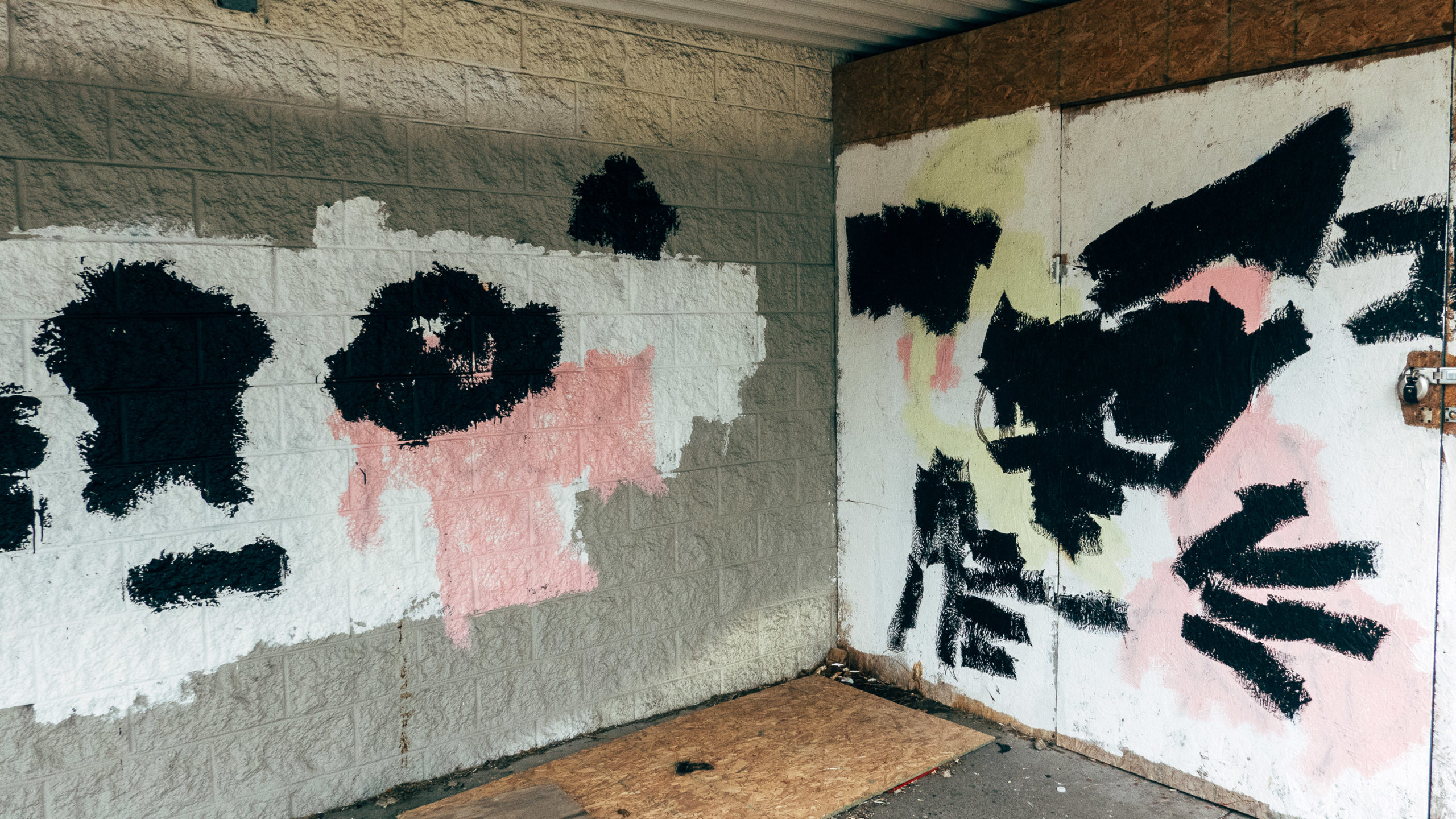 Graffiti covered up with white, pink and black paint