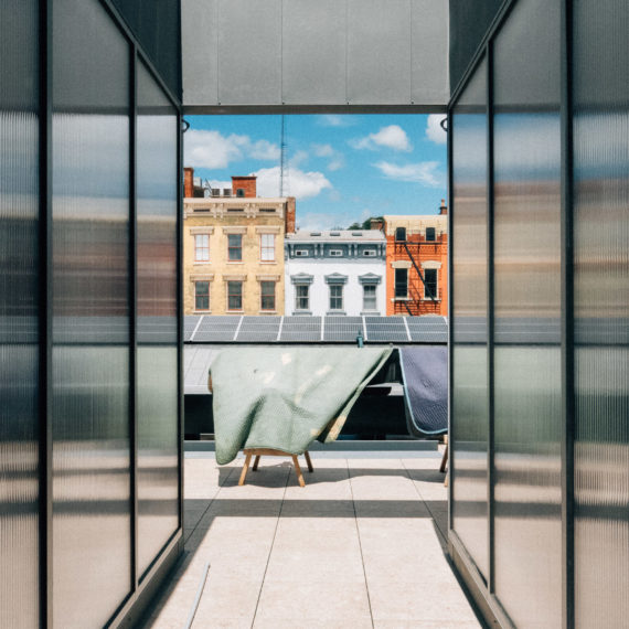 An exterior hallway of reflective surface leading to a city view