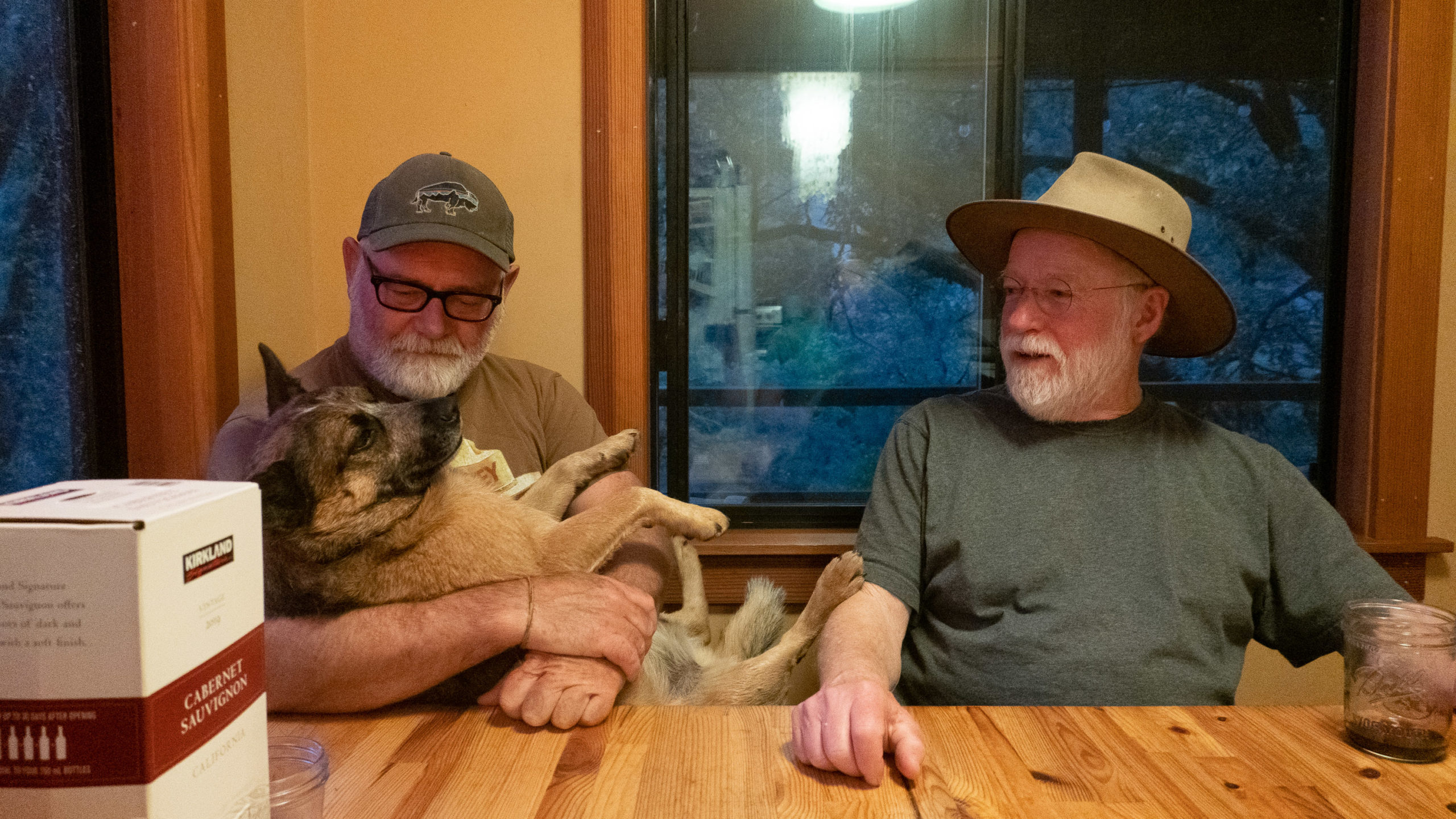 A man holds a dog while another man looks toward them