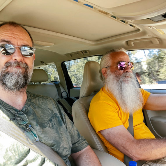 Two bearded men wearing sunglasses in a car with a tan interior