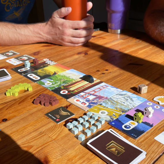 A board game set up on a wooden table in the late afternoon sun