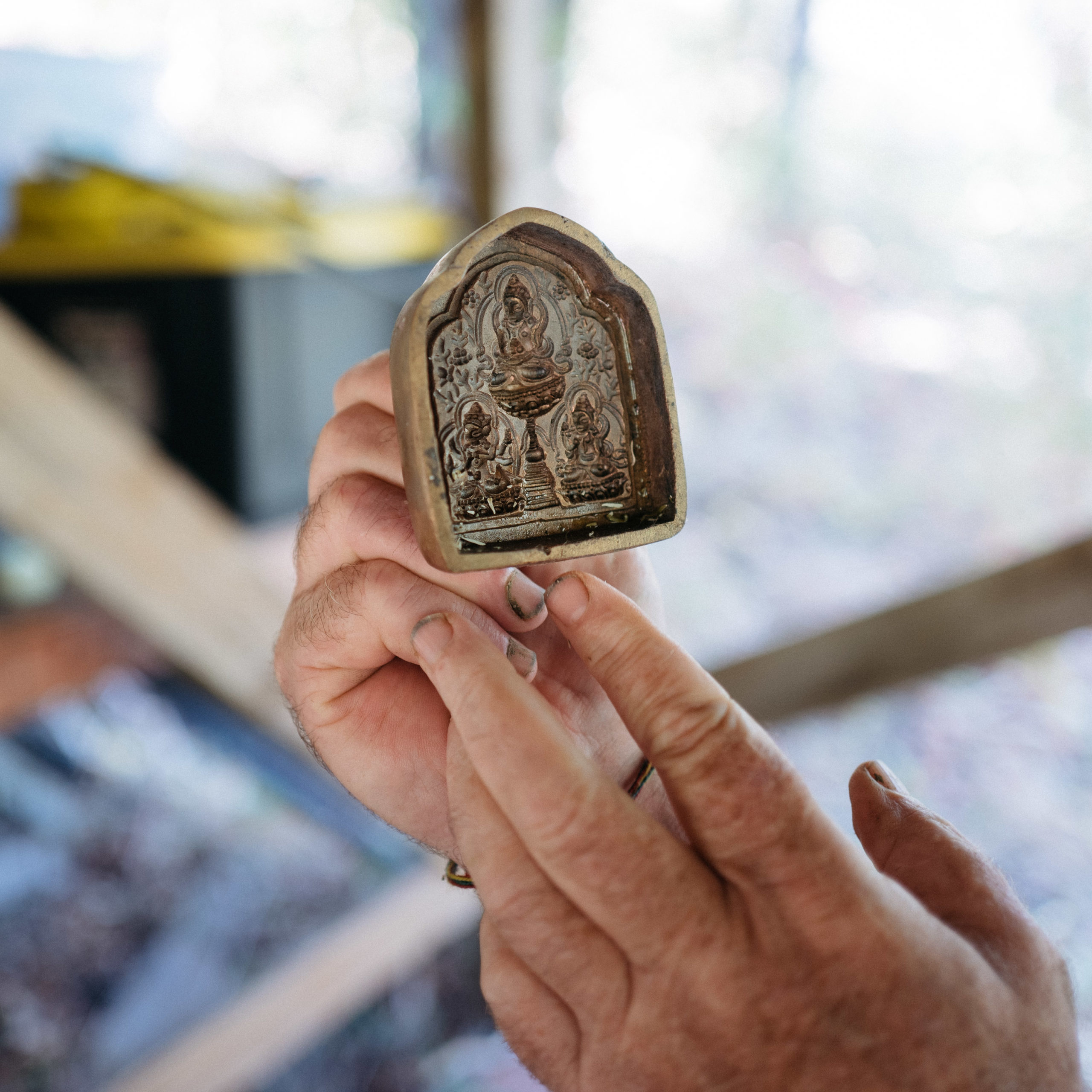 Hands holding a metal tsa-tsa form of Tara