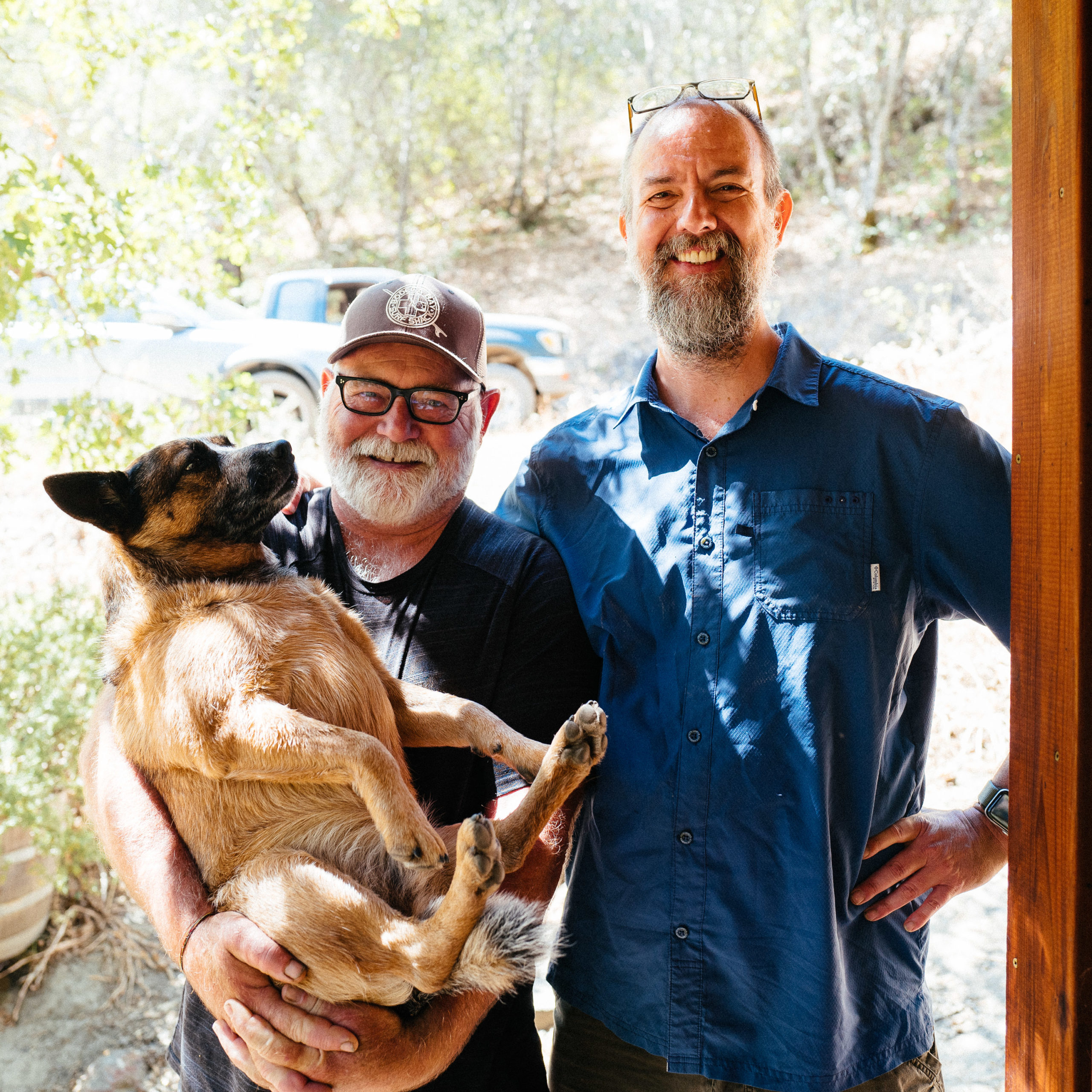 A man holds a dog and another man stands by them