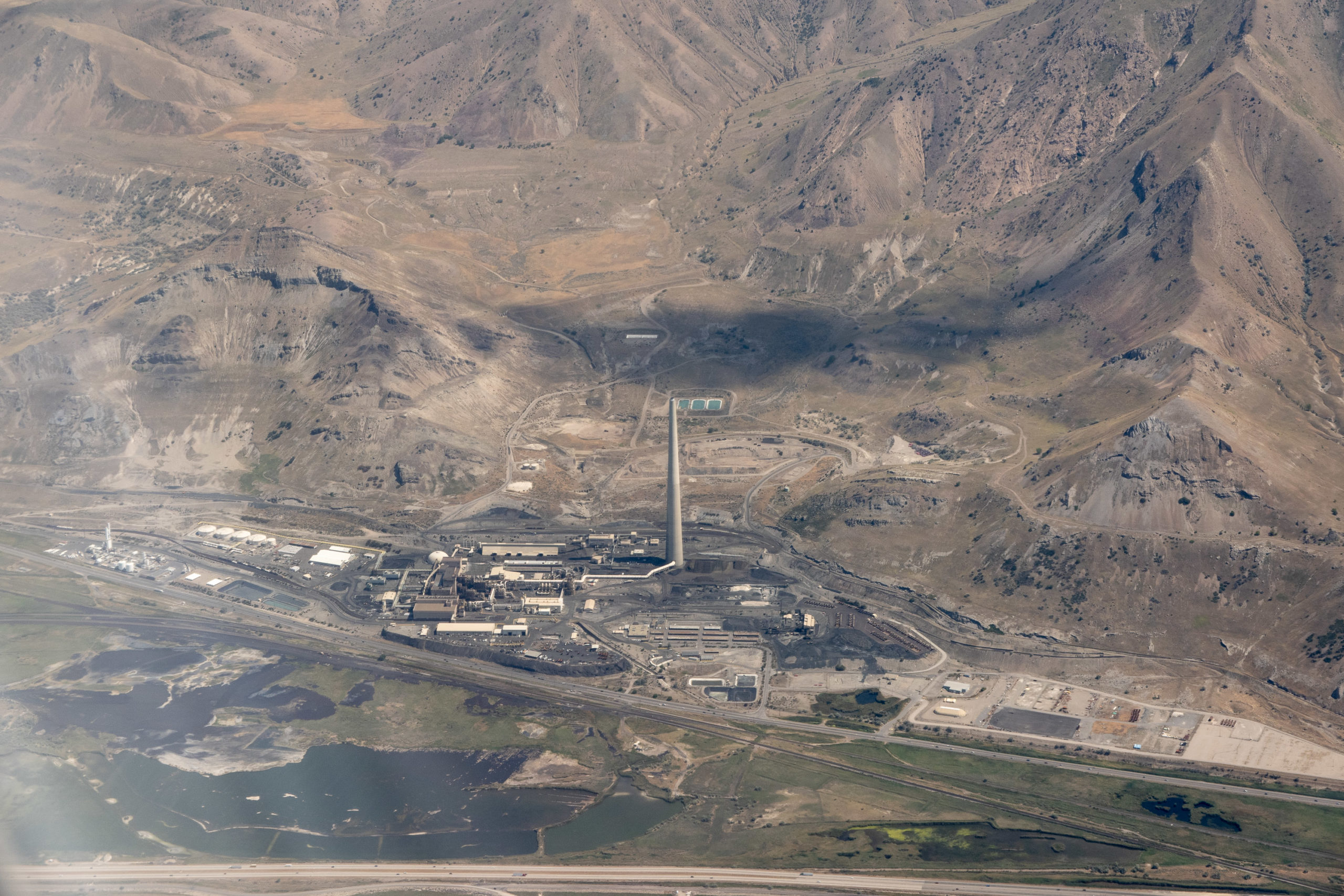 A very tall smokestack at the base of the Oquirrh Mountains