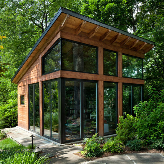 A modern small studio building set in the woods