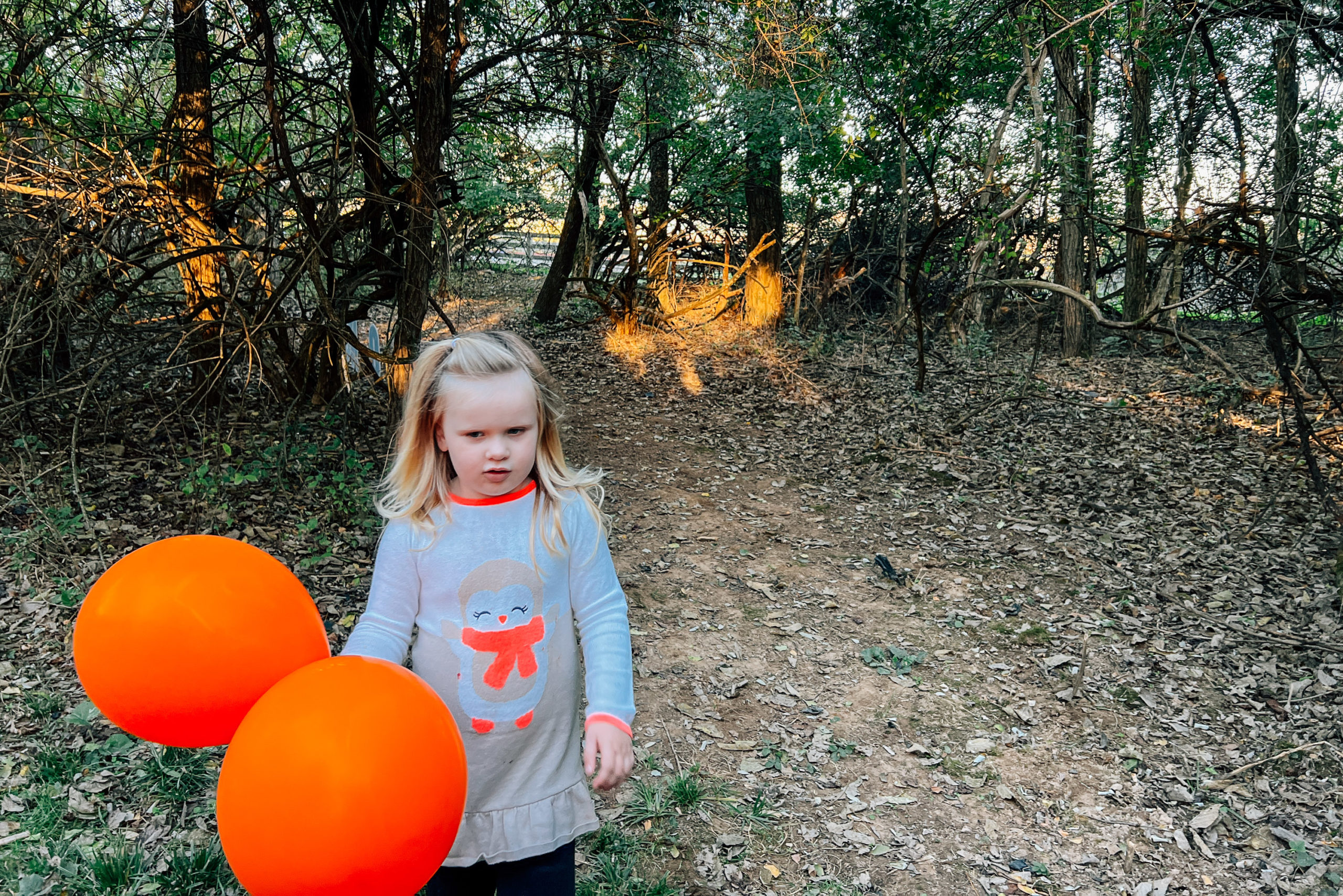 A forlorn girl with two orange balloons