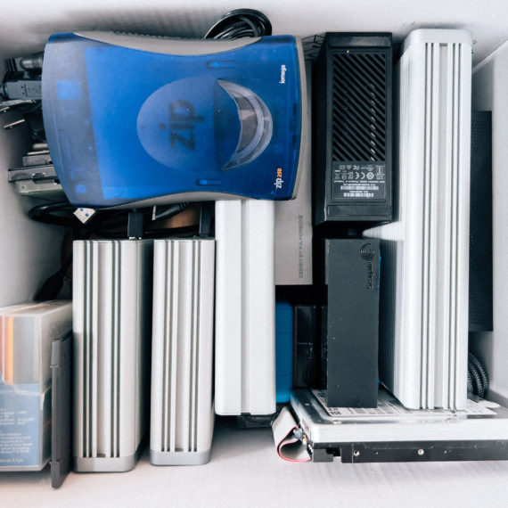 A box filled with external hard drives (and a translucent blue Zip drive)