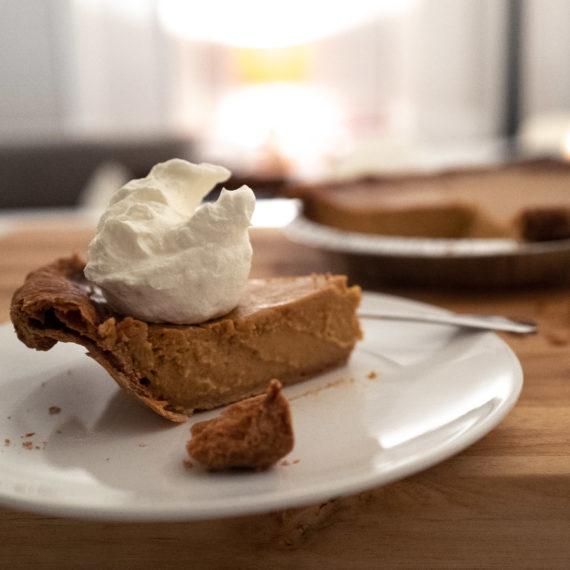 Pumpkin Pie with whipped cream on a wooden countertop