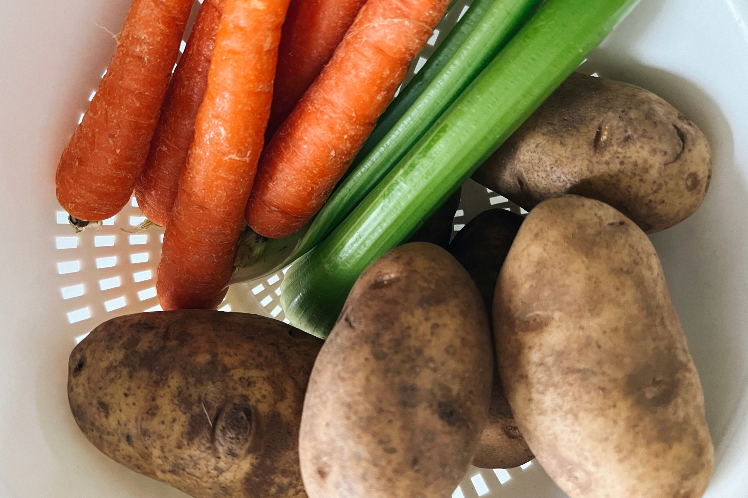 Carrots, celery and potatoes in a strainer