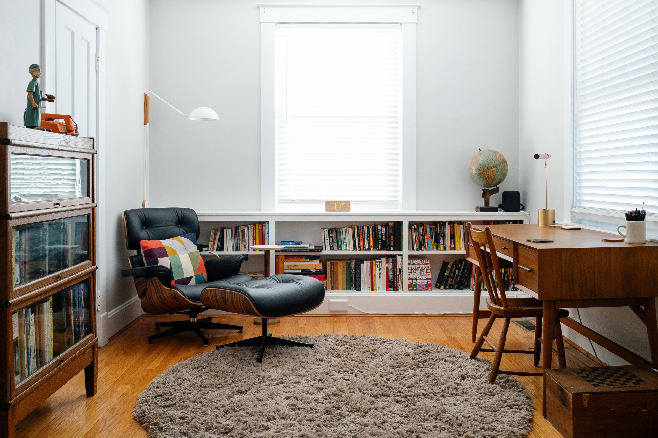 An office with a bookshelf, lounge chair with ottoman and a desk