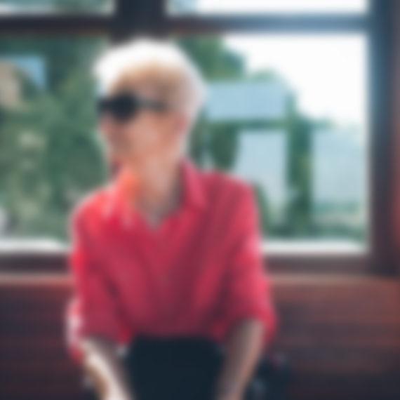 A blurry photo of a woman in a red shirt and sunglasses