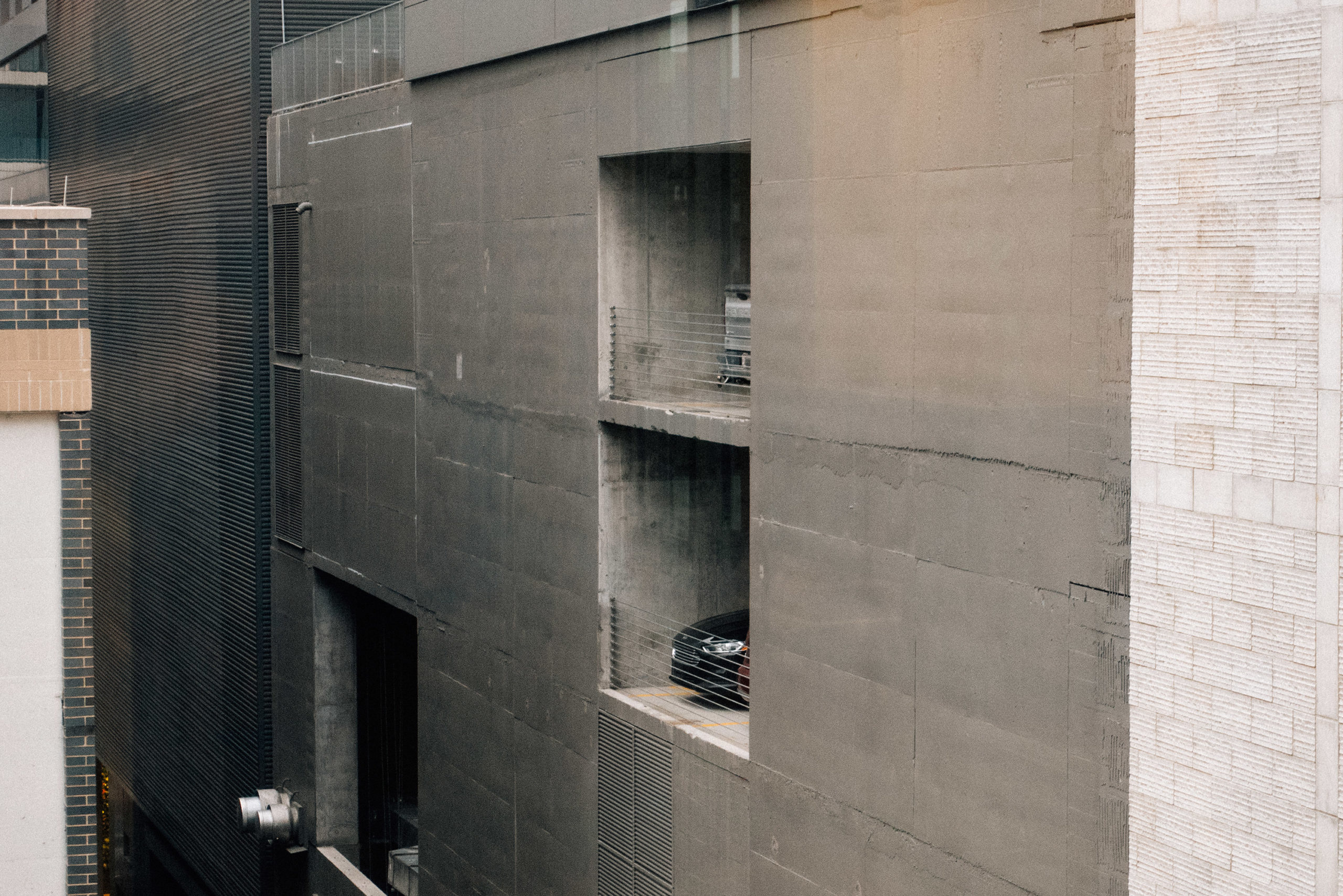 A car peeks out from a concrete building parking garage opening